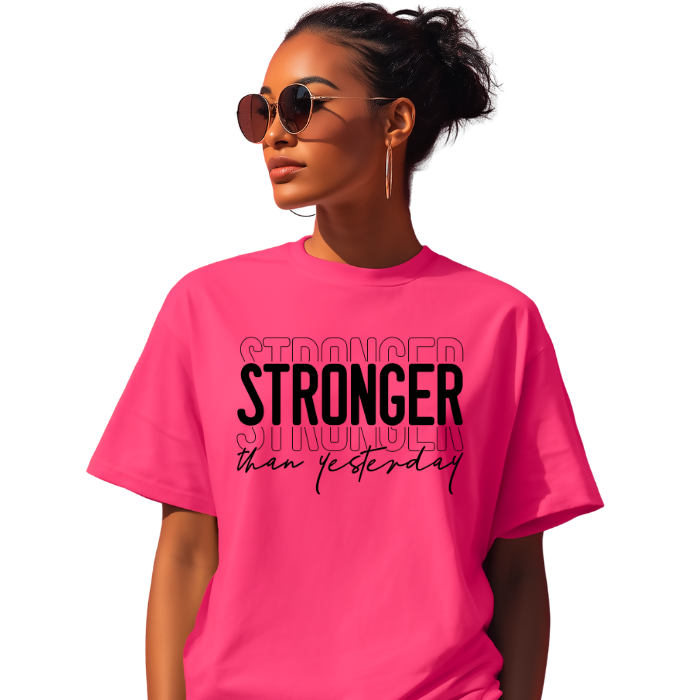 Woman wearing Stronger Than Yesterday graphic tee with bold layered typography in vibrant pink